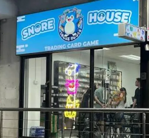 The Snore House shopfront at Lucky Plaza: a sky blue sign with the Snorlax logo above glass doors and a neon Charizard